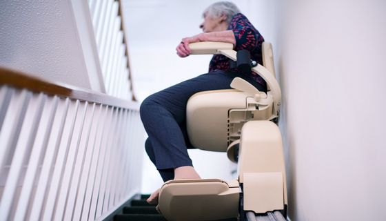 Ältere Frau, nutzt einen Treppenlift.